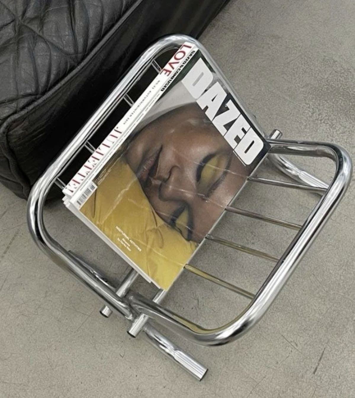 Chrome magazine rack holding design magazines on a concrete floor
