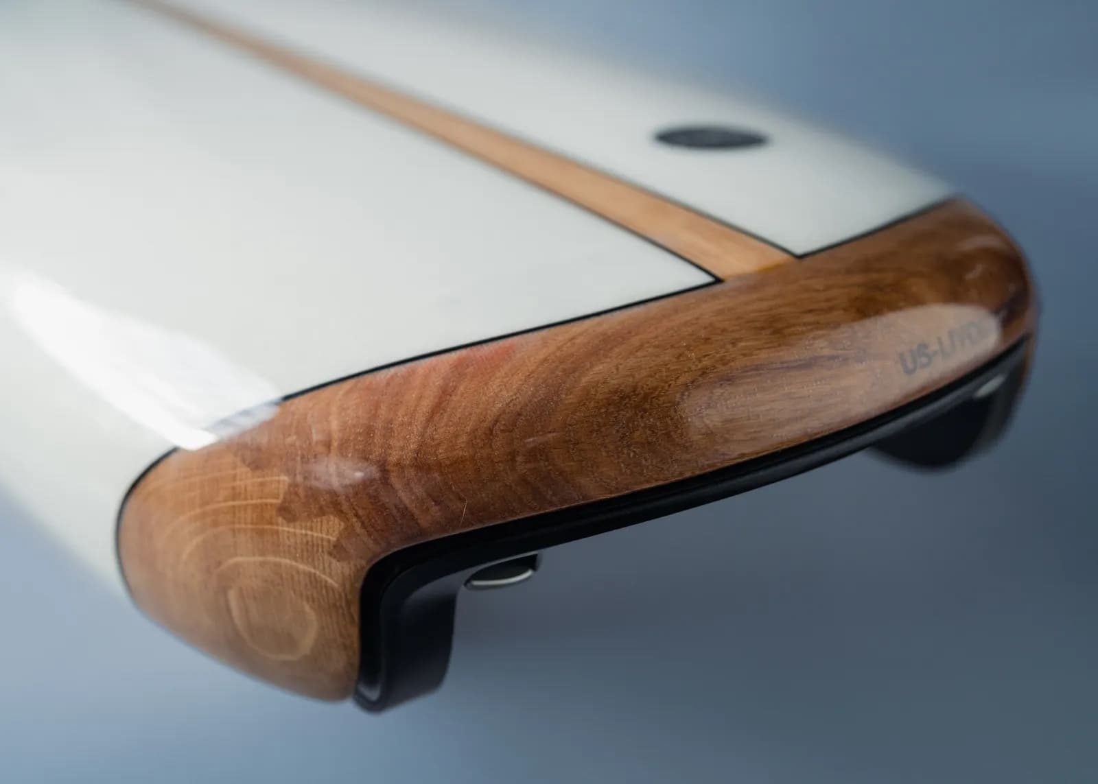 Close-up of the Lind board tail: oak rail, glossy white deck and the jet drive housing